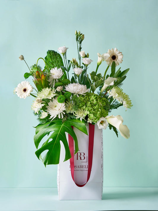 Lily Grace Handbag Arrangement with Calla lilies, lush greenery, and white blooms in a chic handbag, available as special flowers with delivery to Dubai, Sharjah, and Muwaileh.