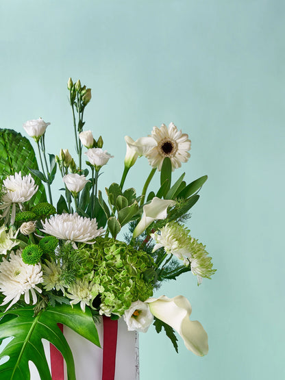 Lily Grace Handbag Arrangement with Calla lilies, lush greenery, and white blooms in a chic handbag, available as special flowers with delivery to Dubai, Sharjah, and Muwaileh.