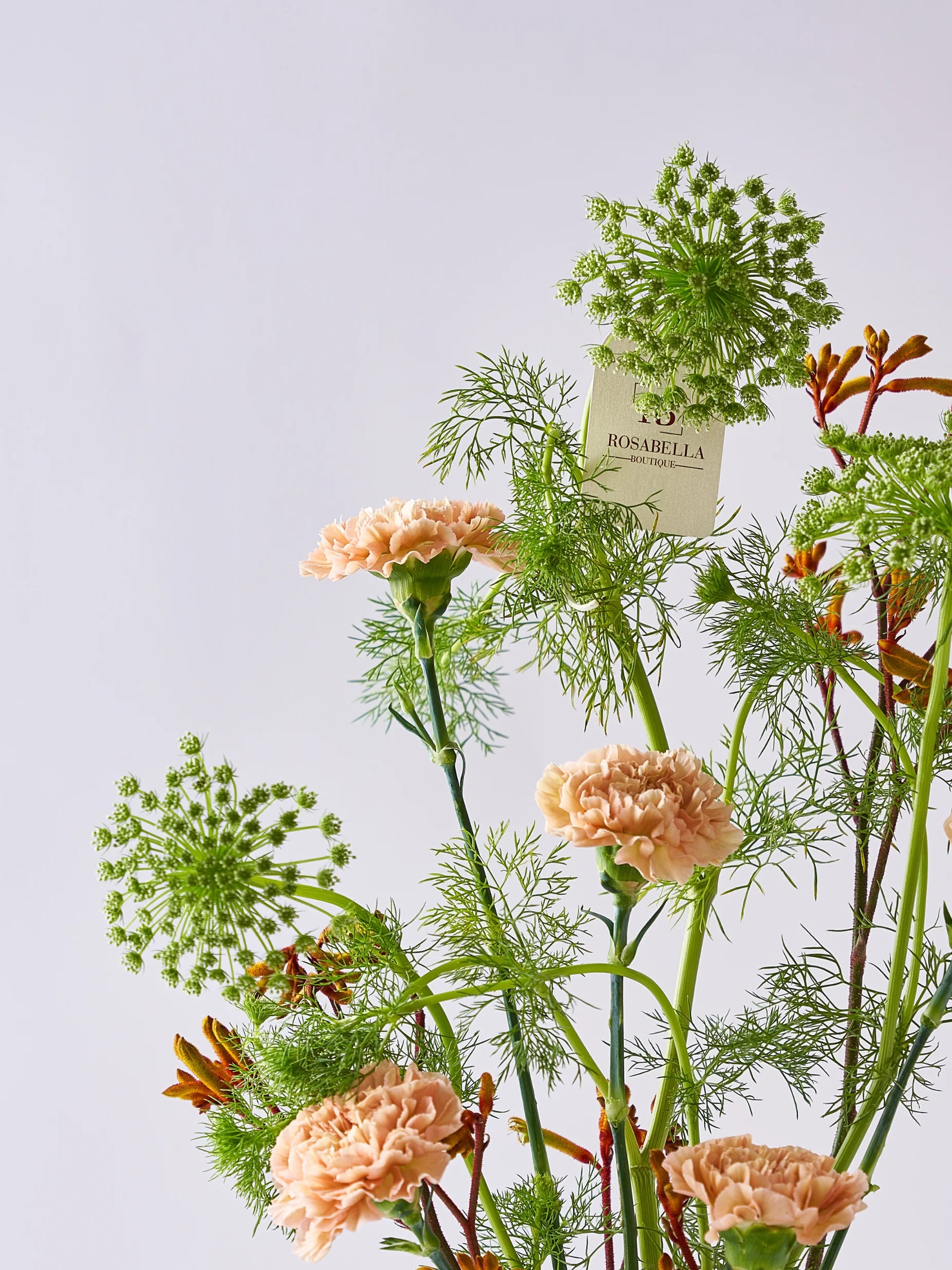 Natural Glow Vase Arrangement with soft peach blooms, lush greenery, and pebble accents in a clear vase, available at a flower shop in Dubai with delivery to Sharjah and Muwaileh.