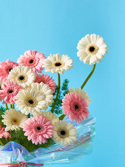 Rainbow Bliss Bouquet with pink and white blooms wrapped in iridescent rainbow packaging, available for flowers delivery to Dubai, Sharjah, and Muwaileh.