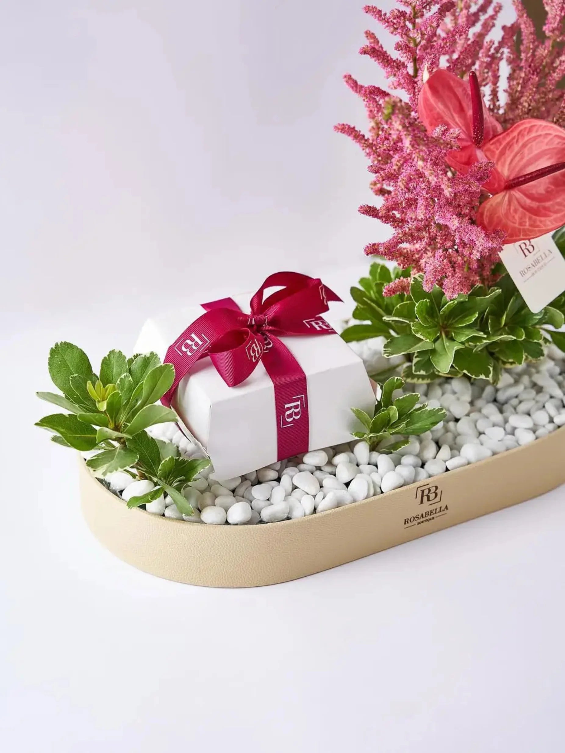 Rosy Luxe Arrangement with vibrant red blooms, lush greenery, and a decadent cake in a premium leather tray, available at a flower shop in Sharjah with delivery to Dubai.