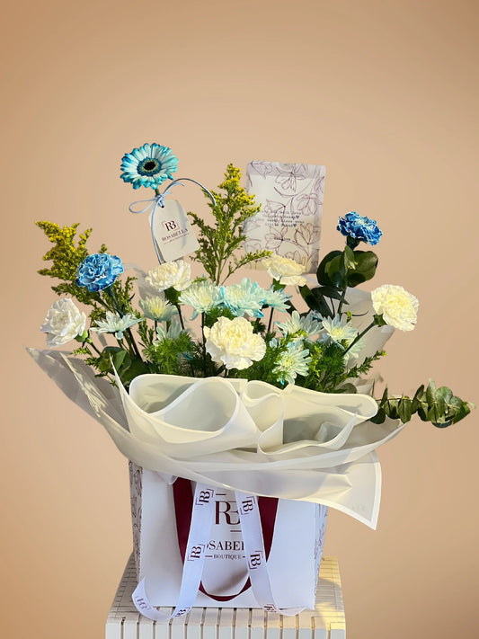 Whispering Blues Handbag Arrangement with blue and white blooms in a chic handbag, available at a flower shop in Muwaileh with delivery to Dubai and Sharjah.